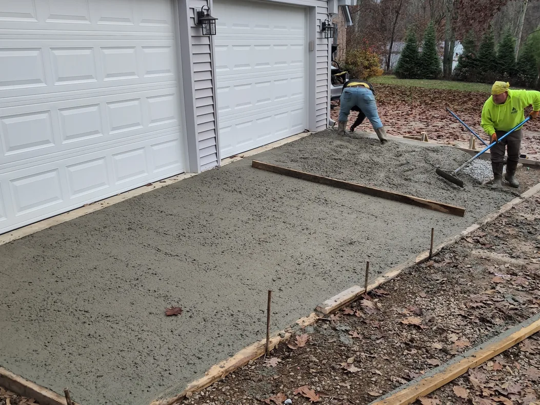 Crew setting forms on a gravel base in front of a garage, concrete contractor