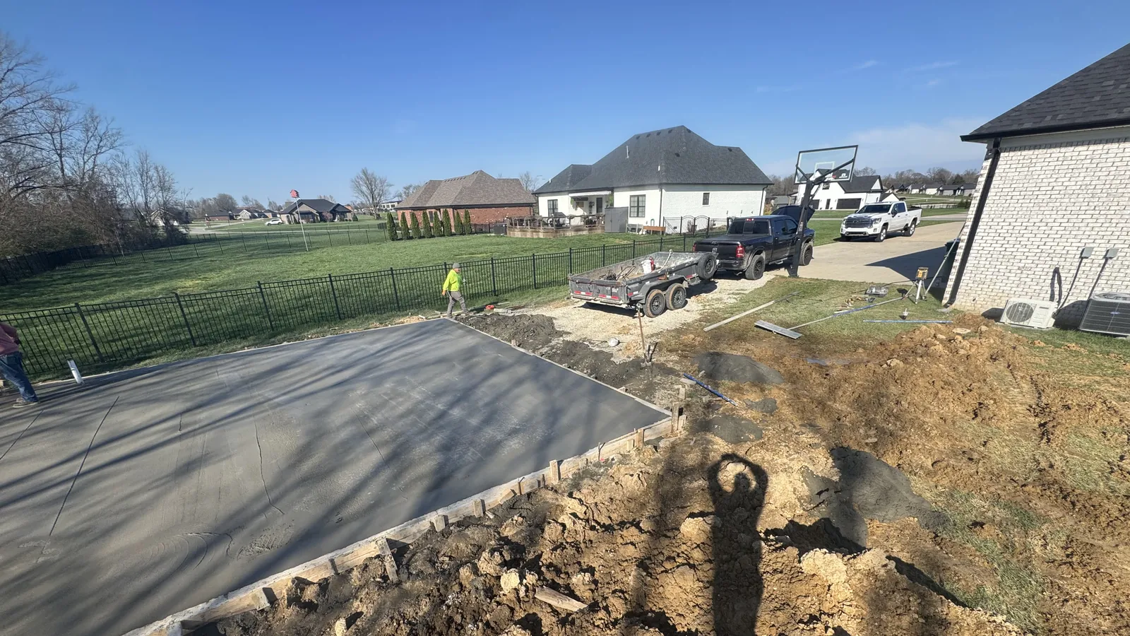 Fresh concrete slab poured beside a newer brick home in a growing subdivision, concrete contractor serving Vine Grove, KY