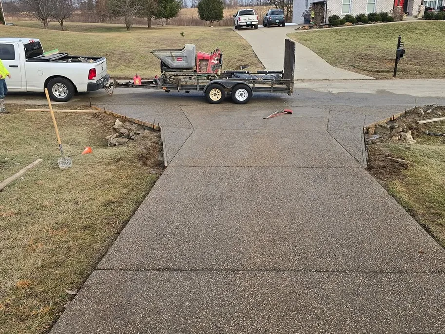 Exposed aggregate concrete driveway addition with a pickup and trailer parked at the top, concrete driveways