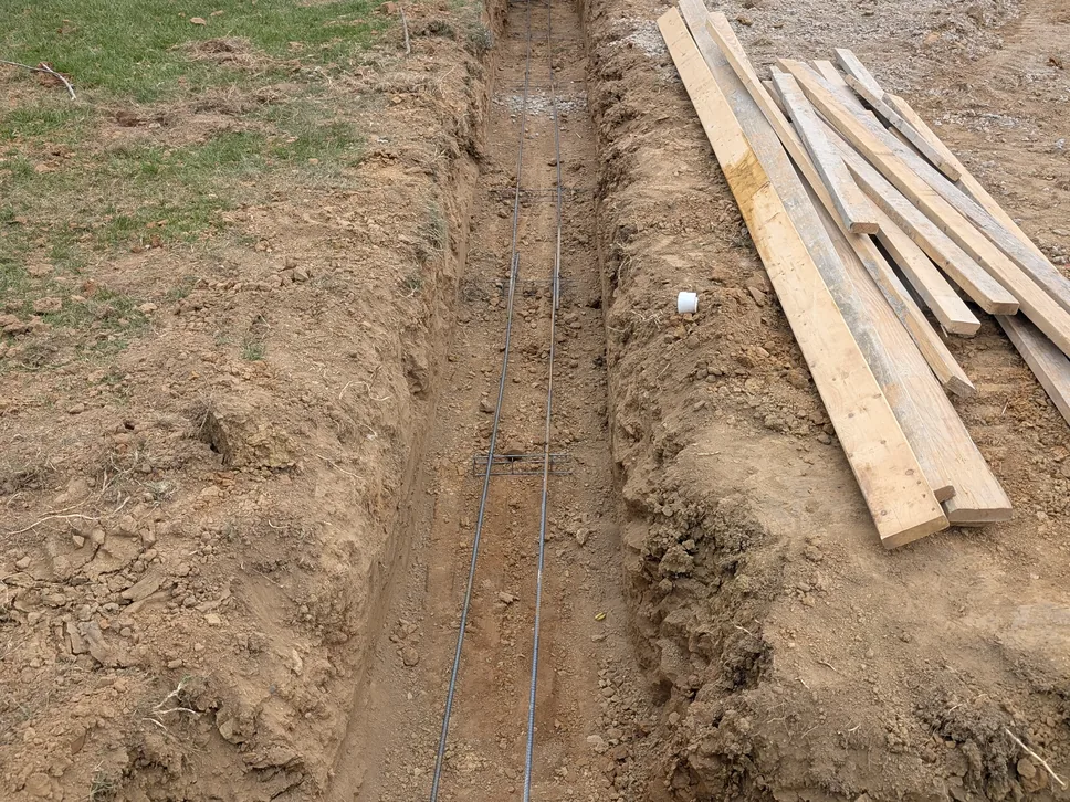 Footing trench with rebar dug along a brick house, concrete foundations