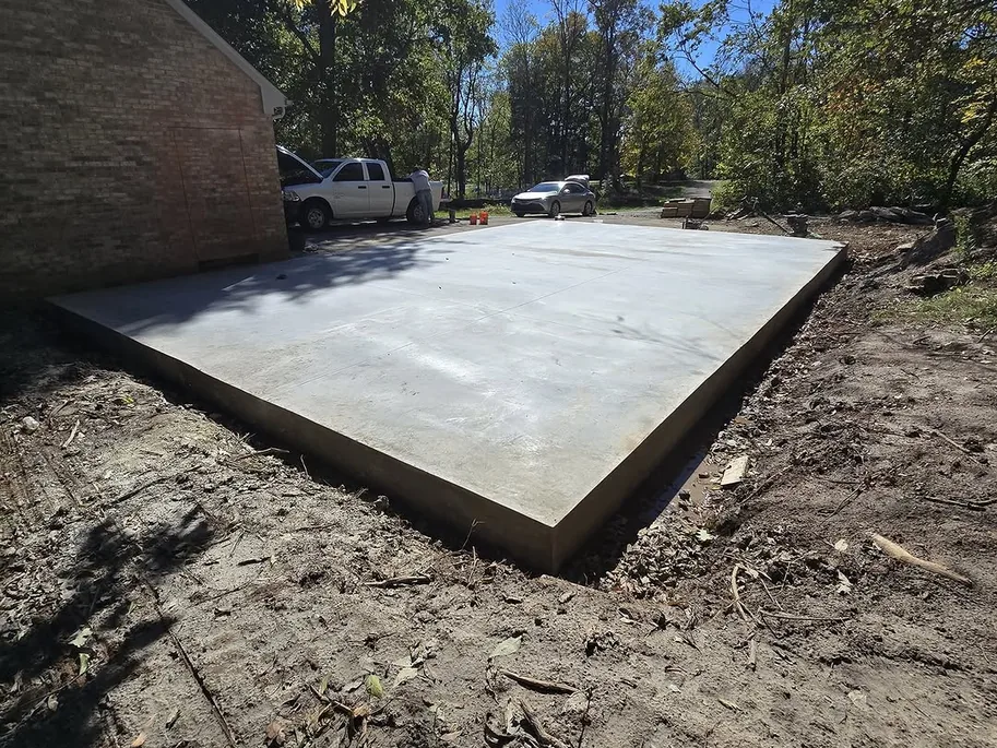 New concrete patio slab in a wooded backyard, concrete patios