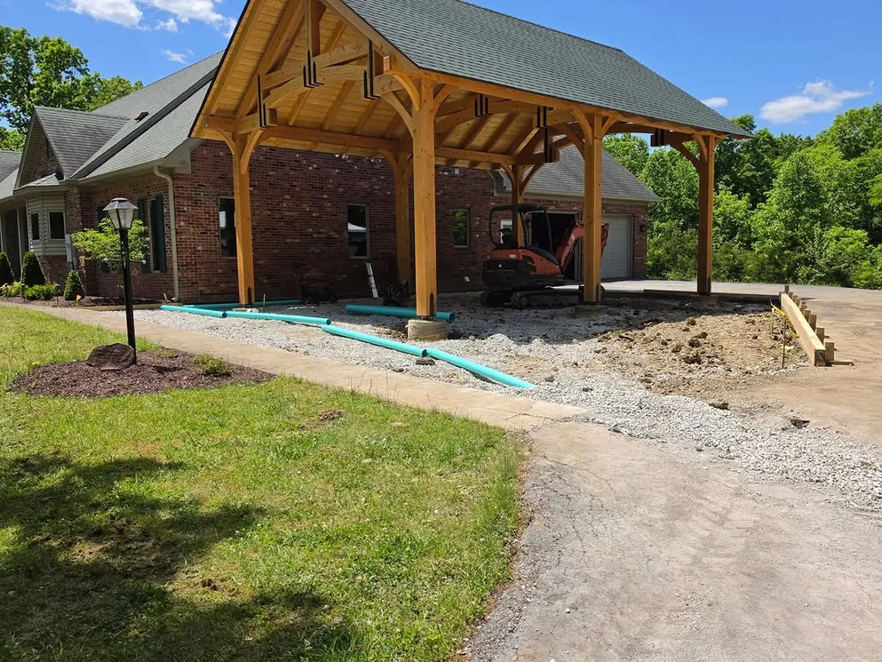 Concrete slab under a timber pavilion beside a brick house, concrete patios