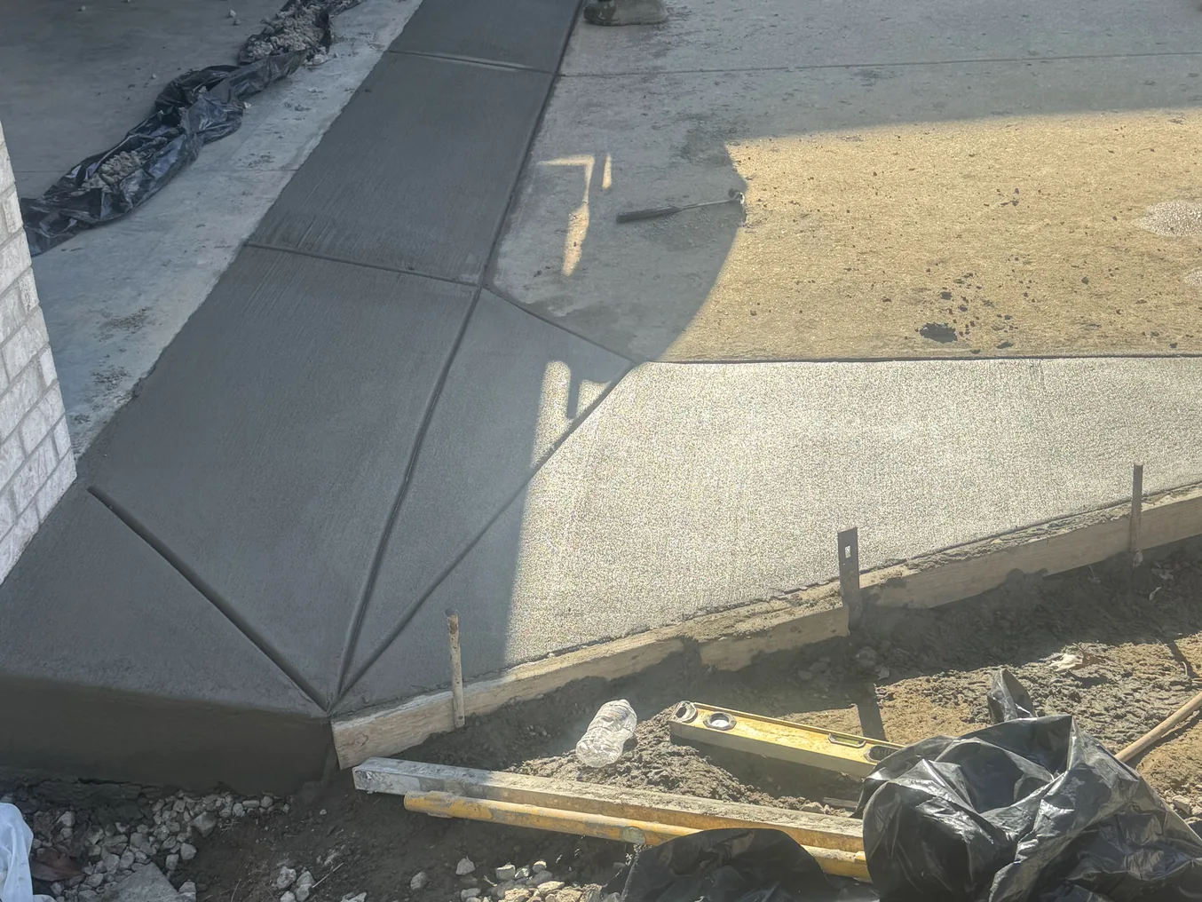 Fresh broom finished concrete walk with tooled joints poured along a brick wall, concrete sidewalks