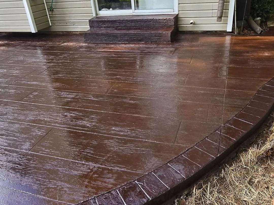 Stamped concrete steps rising from a colored patio to a patio door, concrete steps