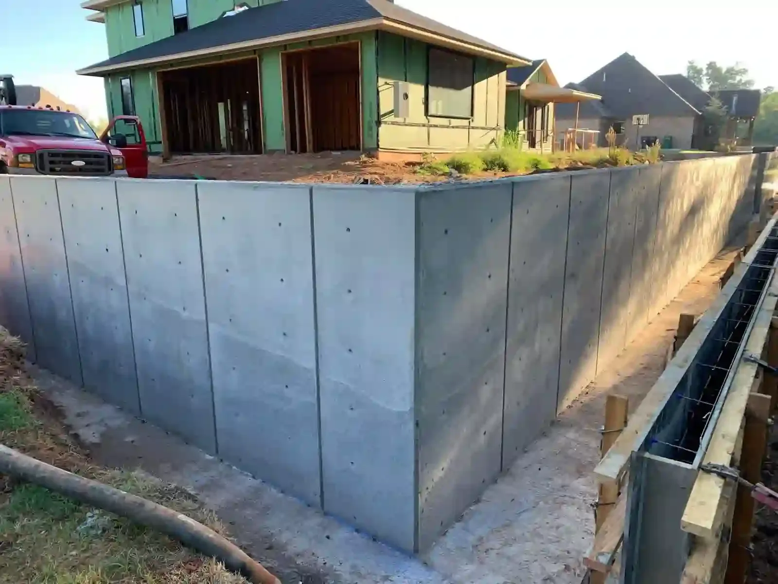 Tall poured concrete retaining wall on a new home lot with the next section in forms, concrete retaining walls