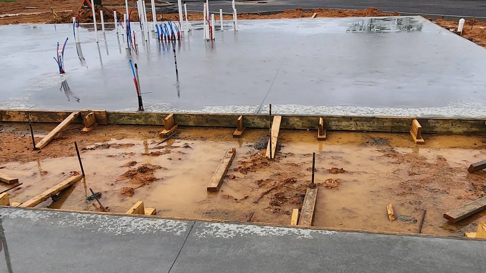 Slab forms and rebar set on a job site under a cloudy sky, concrete contractor