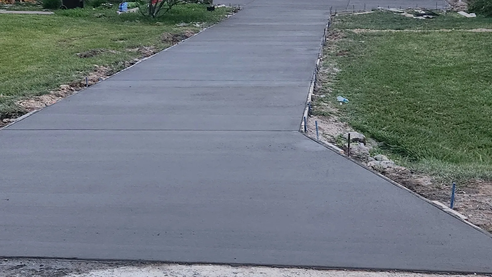 Long new concrete driveway leading up to a house and garage, concrete contractor