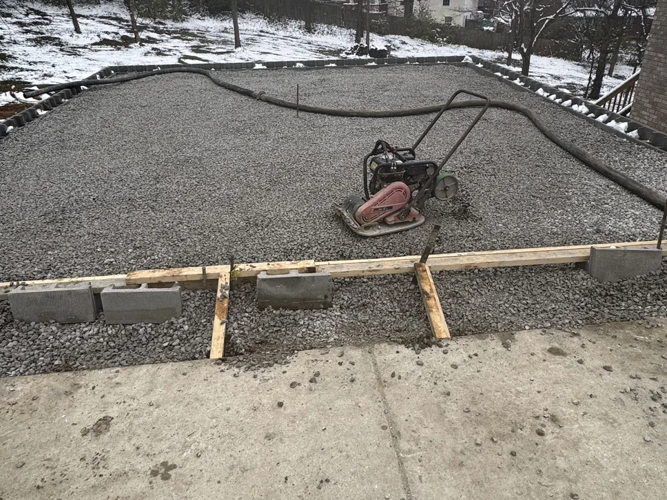 Compacted gravel base inside forms with a plate compactor, site grading