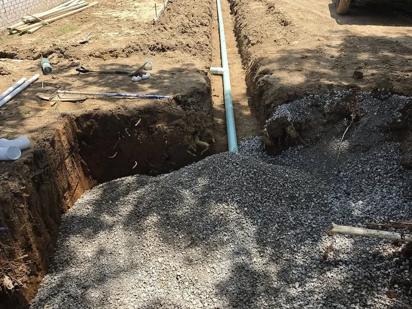 Drainage trench with a pipe and gravel dug before a pour, site grading