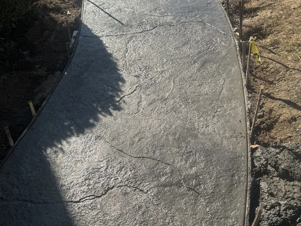 Curved stamped concrete walkway with a stone texture along a slope, stamped concrete