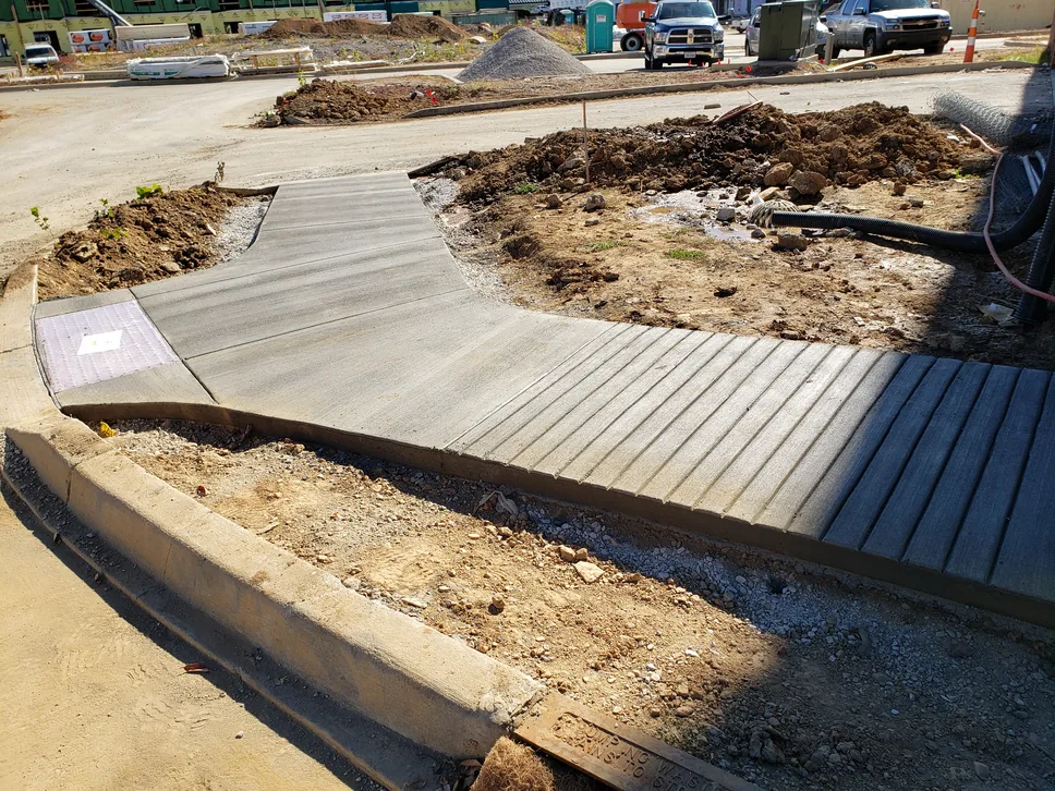 Curved concrete walk with a stamped wood plank section on a new building site, stamped concrete
